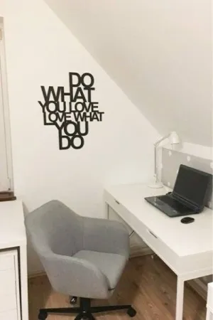 Czarny napis: 'Do what you love, love what you do' wycięty laserem, umieszczony na ścianie w domowym biurze