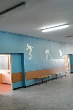 Dekoracje sylwetek sportowych wycięte ze sklejki, umieszczone na ścianie szkolnego korytarza