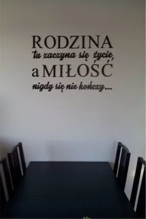 Napis Rodzina tu zaczyna się życie wykonany ze sklejki, umieszczony na ścianie nad stołem
