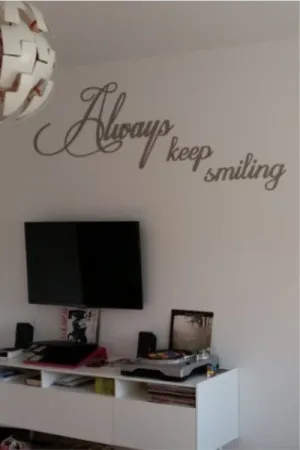 Napis dekoracyjny na ścianie: Always keep smiling w nowoczesnym salonie