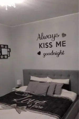 Napis dekoracyjny na ścianie: Always kiss me goodnight w przytulnej sypialni