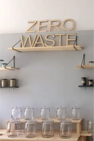 Napis Zero Waste wycięty laserem ze sklejki, umieszczony na półkach w stylu ekologicznym