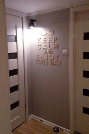 Napis dekoracyjny na ścianie: Keep Calm and Enjoy Your Day, z motywem wąsów w przedpokoju