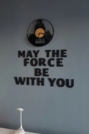 Napis: 'May the Force be with you' wycięty laserem z czarnej sklejki, zamocowany na ścianie z dodatkiem zegara Star Wars