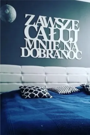 Napis: 'Zawsze całuj mnie na dobranoc' wycięty laserem z białej sklejki, zamocowany na ścianie w sypialni