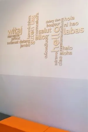 Drewniany napis powitalny hello witaj w roznych jezykach na scianie