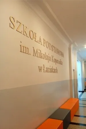 Drewniane litery przestrzenne z nazwa szkoly na scianie korytarza