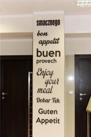 Dekoracyjny napis na ścianie z różnymi wersjami 'smacznego' w różnych językach