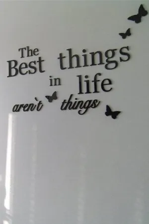 Dekoracyjny napis na ścianie: The best things in life aren't things z motylami
