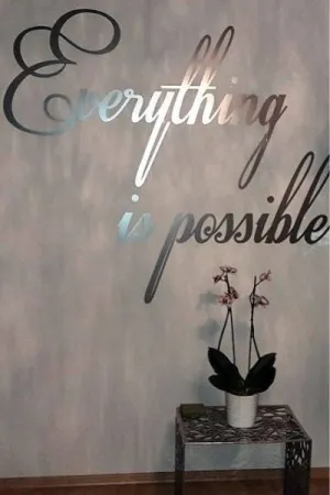 Napis: 'Everything is possible' wycięty z lustrzanej plexi, zamocowany na ścianie w eleganckim wnętrzu