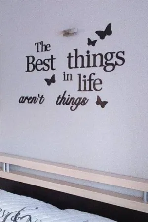 Napis: 'The best things in life aren’t things' z motylkami, wycięty laserem z czarnej sklejki