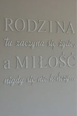 Biały napis: 'Rodzina, tu zaczyna się życie, a miłość nigdy się nie kończy' na ścianie w eleganckim wnętrzu